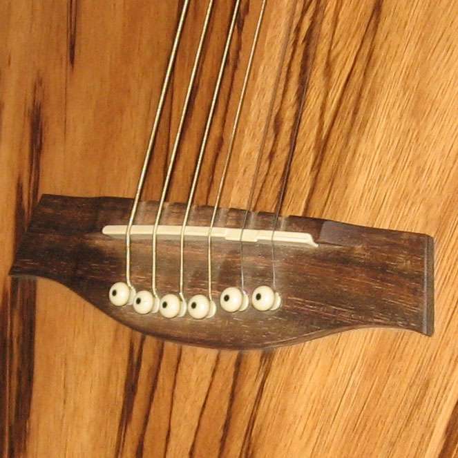 Close real photograph of an acoustic guitar bridge and saddle