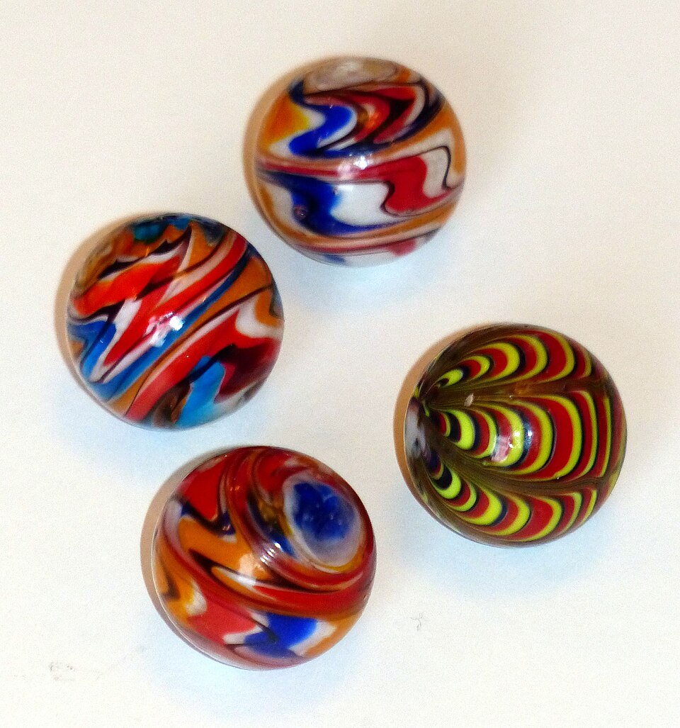 Four real glass swirl marbles photographed individually on white