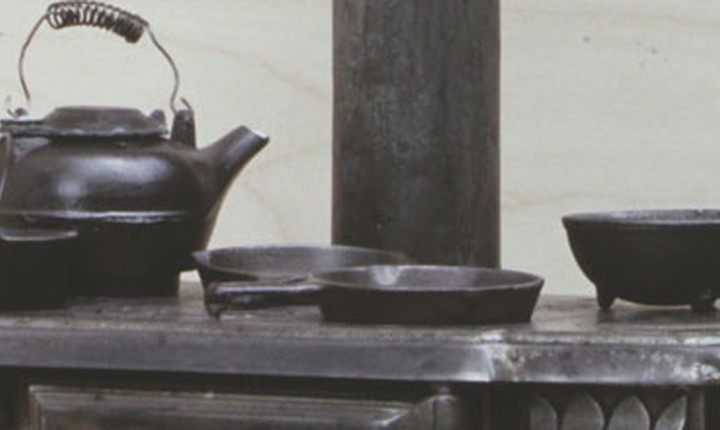 Cropped real Rival toy stove showing its miniature kettle pans and stovepipe