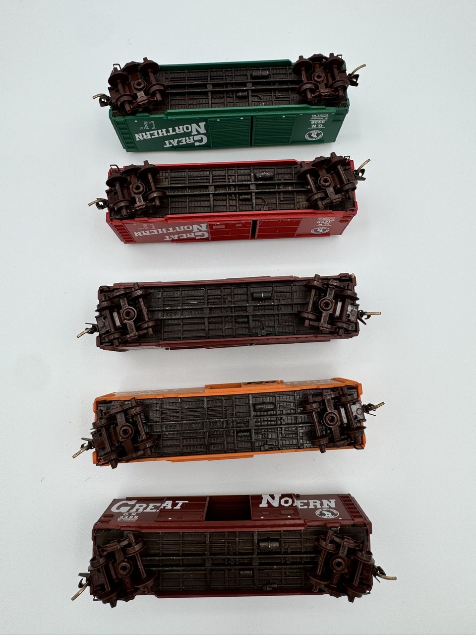 Undersides of five real Micro-Trains cars showing wheels trucks couplers and molded marks