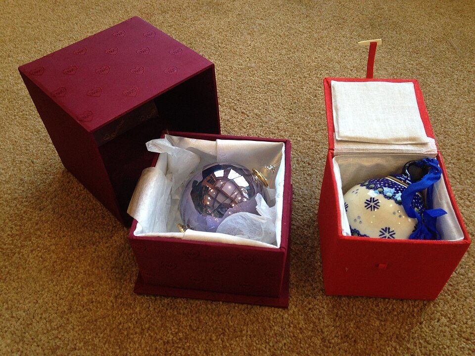 Two glass Christmas ornaments stored in separate decorative boxes rather than factory packaging