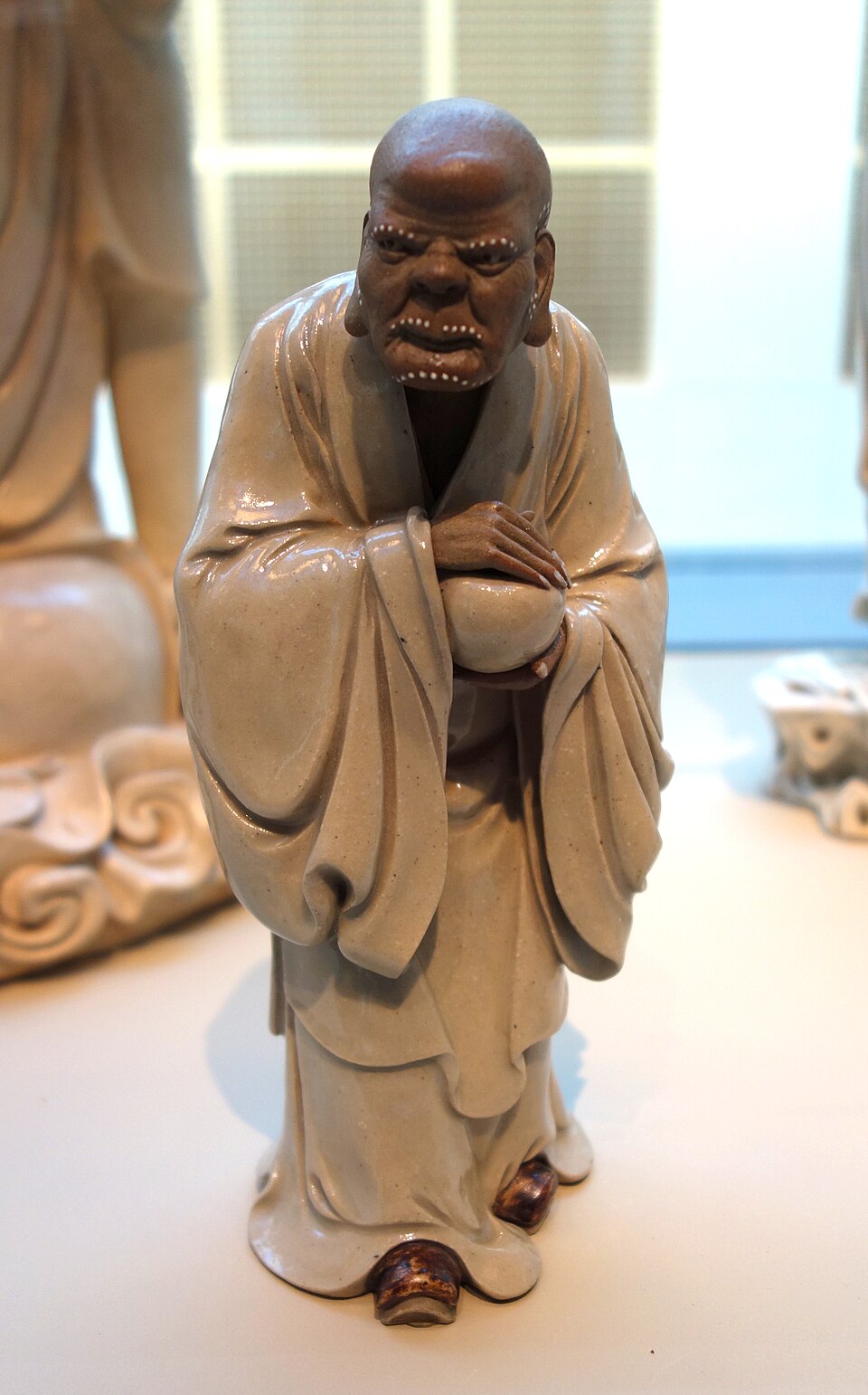Real glazed Shiwan arhat by Liu Chuan showing exposed clay and glossy robe surfaces