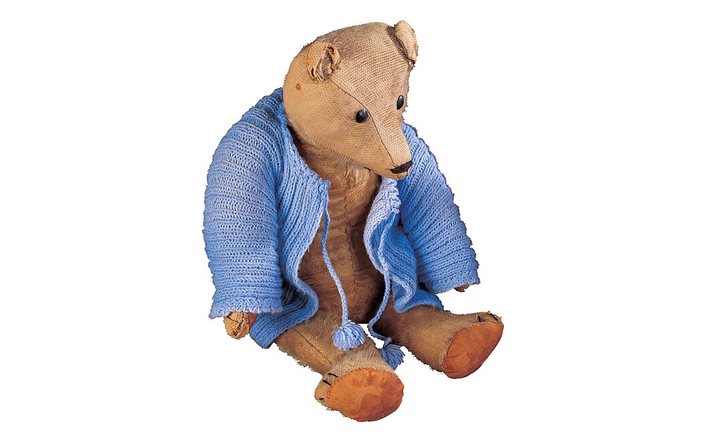 Worn vintage teddy bear with missing fur, a damaged ear, and abraded paw pads
