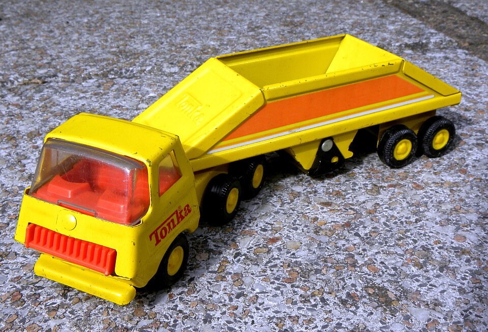Yellow Tonka tractor and bottom-dump trailer with the hopper, wheels, and connecting arrangement visible