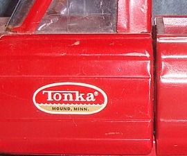 Close photograph of a red pickup door with the oval Tonka decal and Mound, Minn. wording